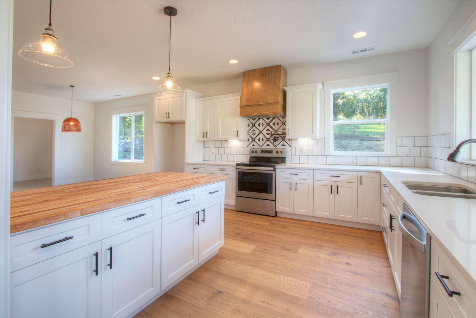 Farmhouse kitchen with white shaker cabinets, wood hood and butcher block island