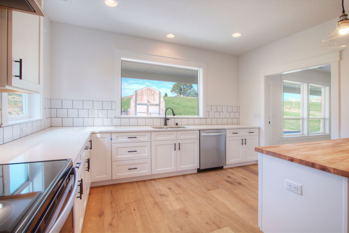 Bright kitchen with light wood floors, white cabinets and a butcher block island
