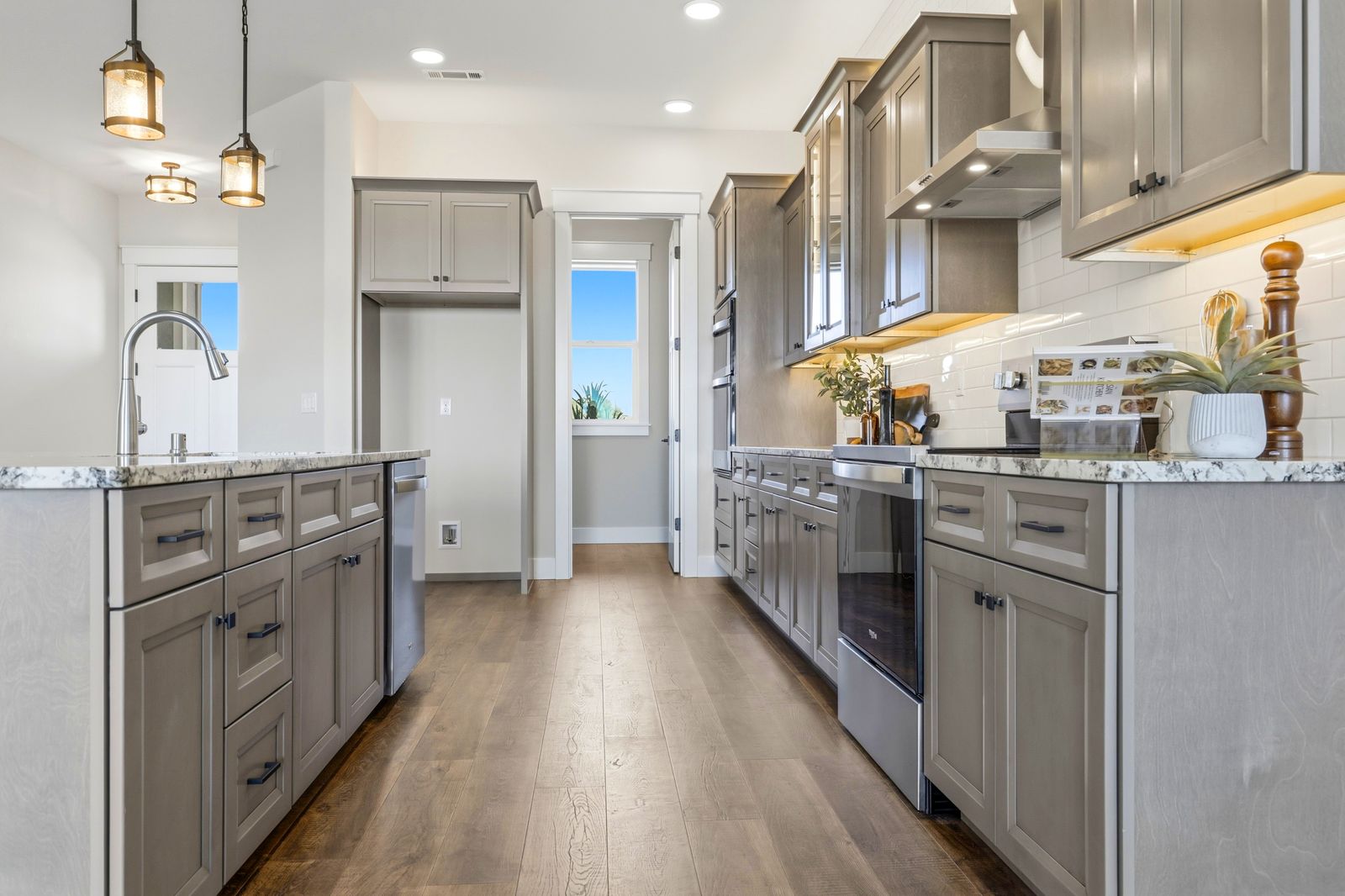 Galley view of a gray shaker kitchen with wood floors