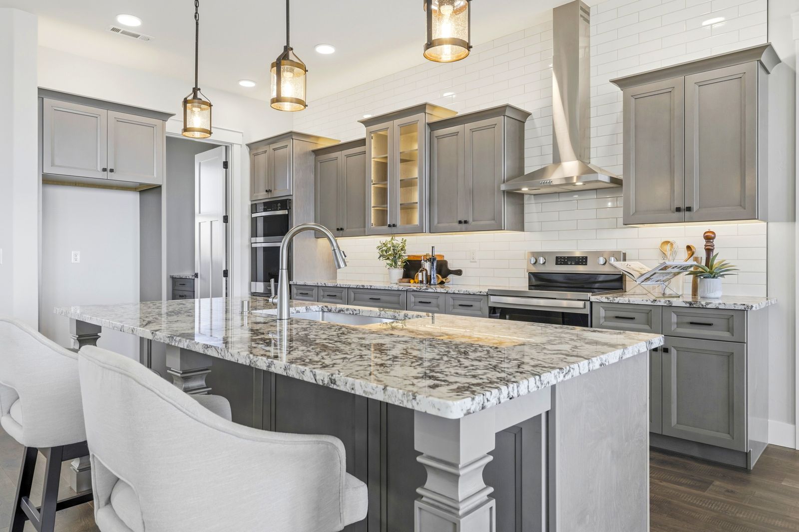 Gray shaker kitchen with white quartz island and chimney range hood